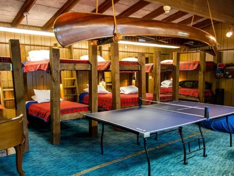 A room with several bunk beds and ping pong table.