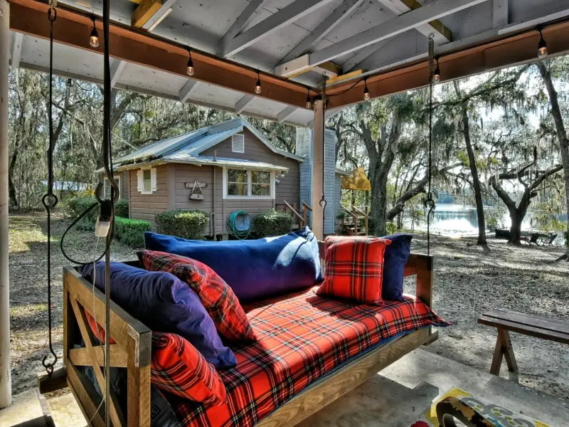 A porch swing with pillows and blankets on it.