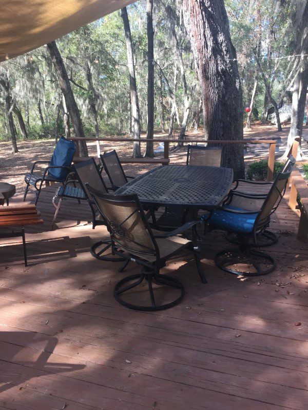 A table and chairs set up in the shade of trees.